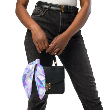 Person holding a black handbag with a colorful scarf draped over it, wearing black jeans and a white top.